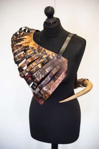 A 3D piece to be worn around the body made from metal resembling ribs and a piece of horn